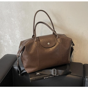 Detailed close-up of dark brown vintage faux leather tote bag with fine grain texture