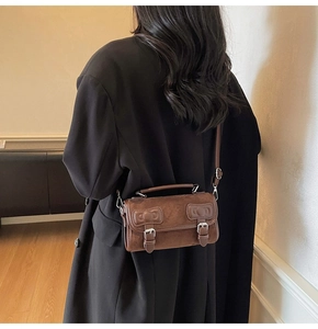 Detail view of dark brown suede crossbody bag styled with a black wool coat