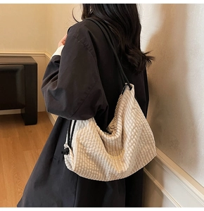 Detail of a large beige gingham tote bag with golden FASHION logo on female model