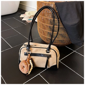 Detail of beige frosted bag with black leather trim and cute donut plush charm