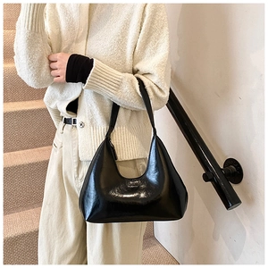 Gros plan du sac hobo en cuir noir brillant avec une bandoulière au design épuré
