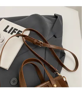 Detail of adjustable dark brown leather shoulder strap with golden metal buckle