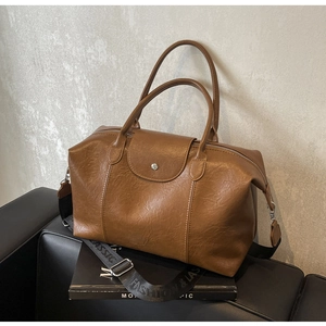 Detailed macro view of brown faux leather boston bag with printed fashion strap