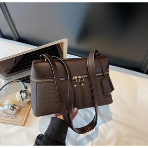 Detail of dark brown square handbag with smooth leather and woven texture in office setting