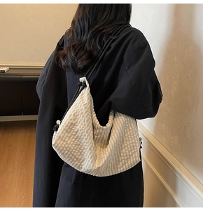 Detail of plaid fabric tote bag with drawstring closure and golden letter embroidery