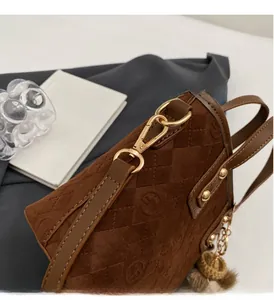 Detailed macro view of vintage brown suede bucket bag with quilted texture and gold hardware