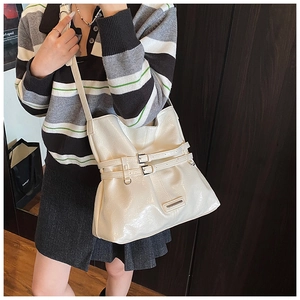 Detail view of cream white tote bag with metal buckles and soft faux leather texture