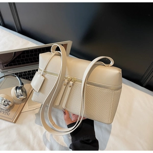Close-up of cream woven leather handbag with double zippers and long shoulder strap