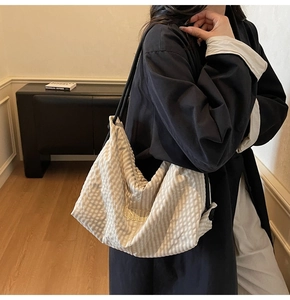 Detail of light beige gingham tote bag with golden FASHION embroidery and black strap