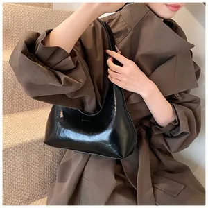 Détail d'un sac à bandoulière en cuir verni noir avec texture plissée et gaufrage mode
