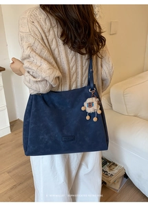 Detail of dark blue frosted leather tote bag with a cute plush sheep charm