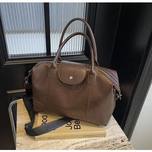 Detail of deep brown leather Boston bag with embossed logo strap and pebble texture
