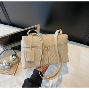 Detailed close-up of beige patchwork handbag with woven texture and double zippers