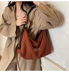 Detail of brown plaid canvas shoulder bag with SHION embroidery worn with a trench coat