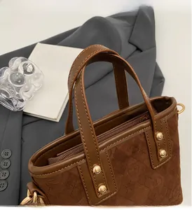 Detail of retro brown bucket bag featuring geometric embossing and gold rivet accents
