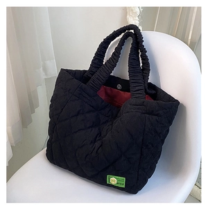 Detailed shot of quilted black tote bag with ruched handle and magnetic closure