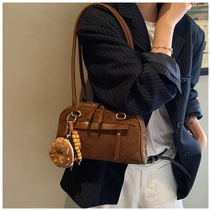 Detail of vintage brown suede shoulder bag featuring a donut plush and colorful bead charm