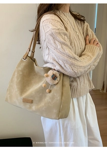 Detail of vintage beige matte tote bag with brown straps and lion plush charm