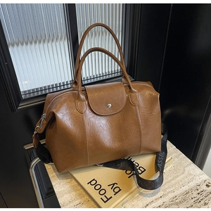 Detail of vintage brown faux leather Boston bag with metal buckle and woven strap