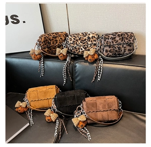 Close-up of stylish crossbody bags with leopard prints and scalloped edges with charms