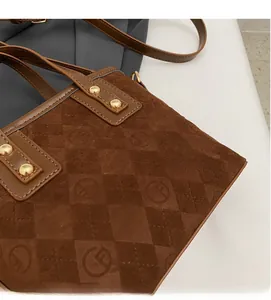 Close-up of brown suede bucket bag featuring embossed geometric patterns and gold rivets