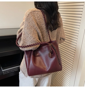 Detail showing the burgundy woven tote bag texture and wide braided shoulder straps