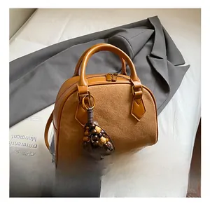 Detail of caramel brown pillow bag with beaded tassel, leather and suede texture contrast