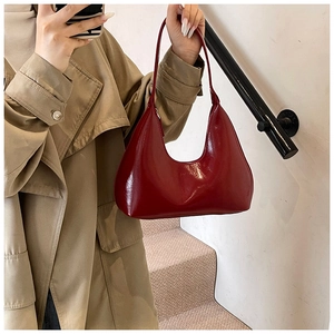 Gros plan d'un sac hobo rouge brillant porté par un mannequin en trench-coat pour le style