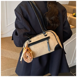 Detail of matte beige shoulder bag with black leather straps and donut plush pendant accessory