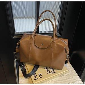 Detailed view of brown Boston bag with retro lychee texture and FASHION wide strap