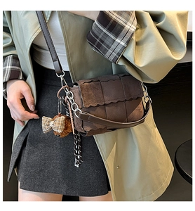 Detail of brown suede crossbody bag with woven texture and cute plush bear charm