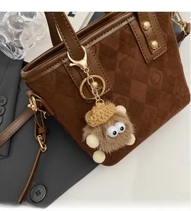 Detailed close-up of a brown quilted bucket bag with a plush charm and gold hardware