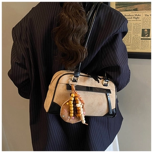 Detail of vintage boston bag with contrast trim and beaded donut pendant in a studio setting