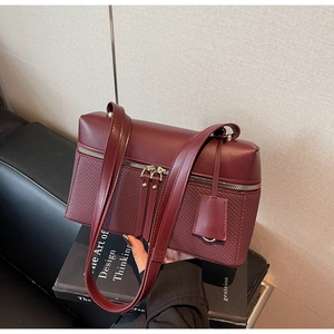 Detail of burgundy textured crossbody bag with diamond weave and double zip design