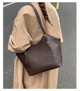 Details der dunkelbraunen Tragetasche mit Vintage-Textur und goldener Schnalle am Trenchcoat