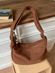 Sac hobo en daim marron avec motif léopard et breloque en perles de bois sur banc en bois