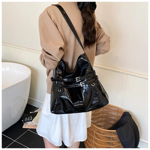 Close-up of black patent leather shoulder bag with silver metallic buckle details