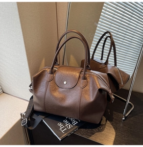 Detail of dark brown lychee texture leather Boston bag with a wide fabric strap
