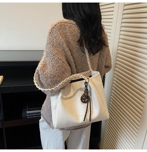 Detailed shot of large white tote bag featuring woven handles and round cutout charm accessory