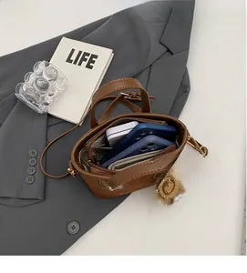 Close-up of brown bucket bag interior with compartments holding two smartphones