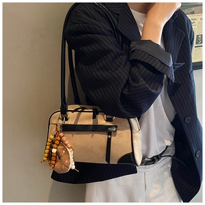 Detail of retro beige matte shoulder bag with black leather trim and donut charm