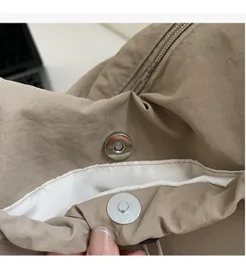 Dettaglio di fibbie magnetiche argentate su una borsa in nylon marrone con effetto metallico