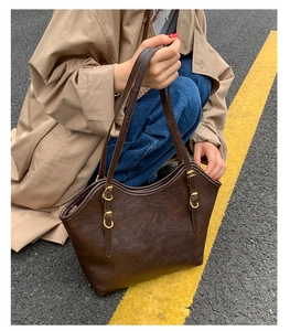 Detail der dunkelbraunen Leder-Shopper mit Vintage-Textur und goldenen Metallschnallen