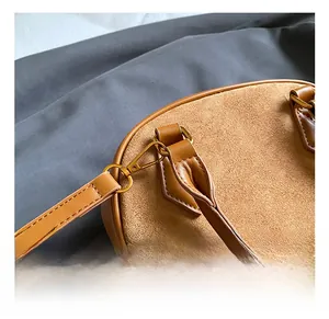Close-up of premium gold-tone metal hook and stitching on brown faux suede shell bag