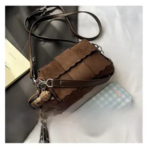 Detail of dark brown suede crossbody bag with wide weave pattern and wavy edge flap