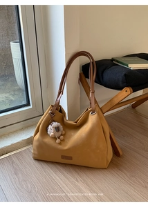 Detail of ginger yellow matte tote bag with brown straps and white plush sheep charm