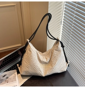 Detail of checkered tote bag featuring gold embroidery and black rope handles on a table