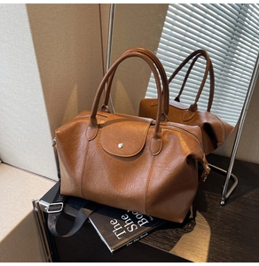 Detail of caramel brown textured leather tote with double handles and wide nylon strap