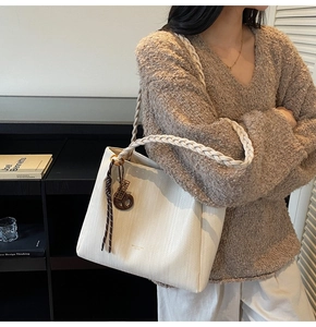 Close-up of beige woven tote bag with braided strap and dark brown resin ring detail