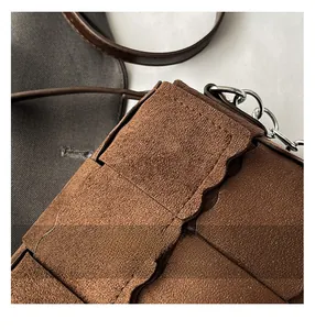 Close-up of the woven brown suede texture and metal chain strap of the crossbody bag